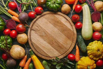 Variety of colorful vegetables by cutting board on dark wooden table - Powered by Adobe