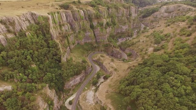 Cars driving on winding scenic road in beautiful valley, aerial drone shot