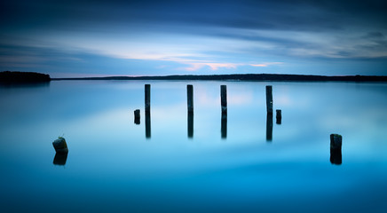 Obraz premium Lake with wooden posts after sunset, long exposure