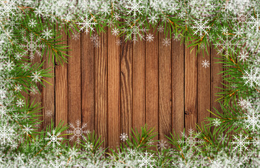 Frame with twigs of Christmas tree and snowflakes on wood