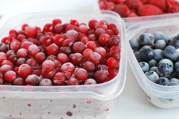 Frozen berries (cranberries, blueberries, raspberries) in plastic boxes.