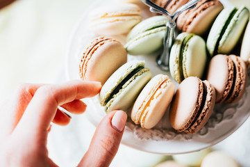 Homemade French Macaroons on the Plate, Pistachio, Coffee and Vanilla Macaroons, Womans Hand is taking Delicious Cookies Macaroons, Beautiful Wallpaper