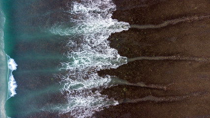 Aerial above ocean waves on a sandy beach surface