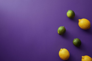 top view of limes and lemons on violet surface
