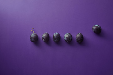 top view of ripe plums on violet surface