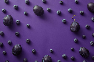 top view of blueberries and plums on violet surface