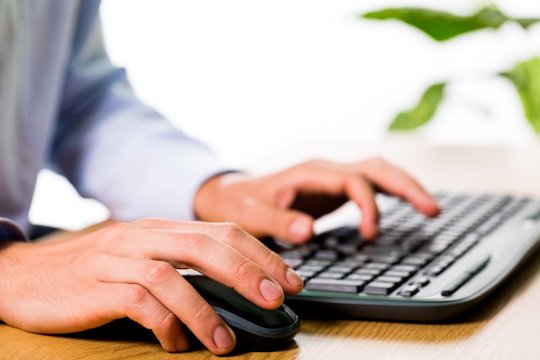 Closeup of an Employee Typing on Keyboard and Holding Mouse