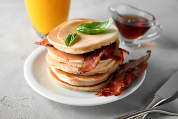 Tasty pancakes with fried bacon on table