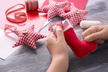 Child making felt Christmas toy at wooden table