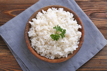 Bowl with boiled white rice on wooden table