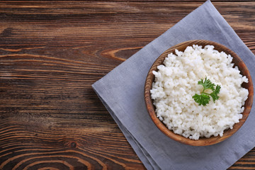 Bowl with boiled white rice on wooden table