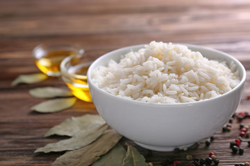 Bowl with boiled white rice on wooden table