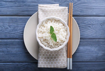 Bowl with boiled white rice on wooden table