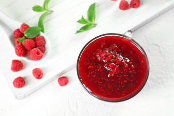 Bowl with tasty raspberry jam on white table