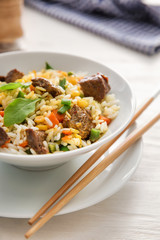 Delicious boiled rice with meat and vegetables in bowl on table