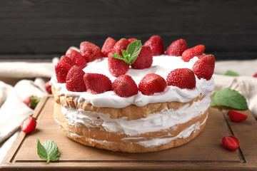 Delicious cake with strawberries on wooden board