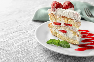 Plate with piece of delicious strawberry cake on table