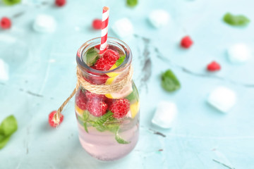 Glass bottle of fresh raspberry mojito on light table