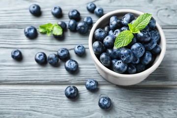 Bowl with ripe blueberries on wooden table