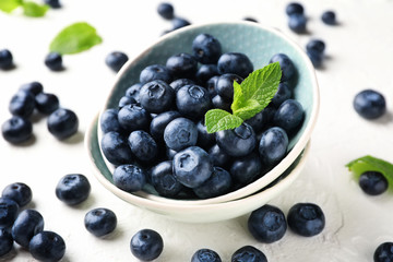 Bowl with ripe blueberries on light table