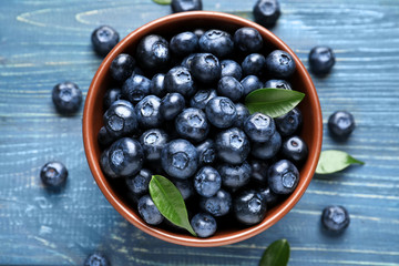 Bowl with ripe blueberries on wooden table