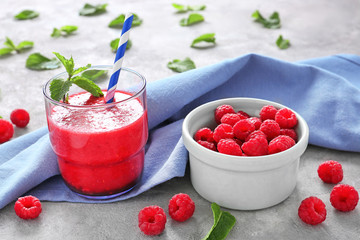 Glass of tasty raspberry smoothie and bowl with fresh berries on table