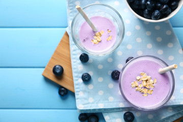 Glasses with tasty blueberry smoothie on color wooden table