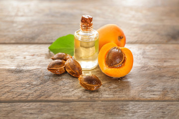 Apricots and bottle of essential oil on wooden table