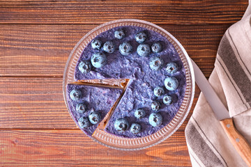 Stand with tasty blueberry cheesecake on wooden table