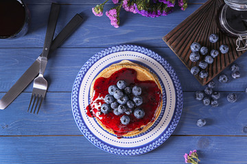 Plate with tasty pancakes, jam and blueberries on wooden table