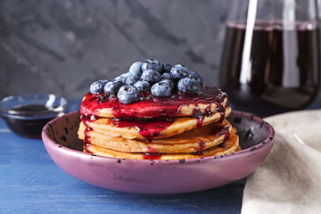 Bowl with tasty pancakes, jam and blueberries on wooden table, closeup