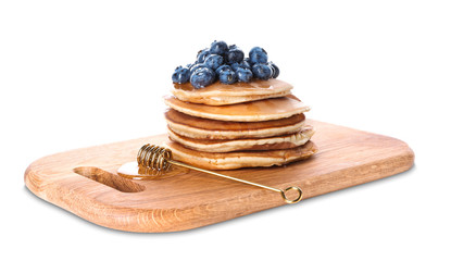 Board with tasty pancakes, blueberries and honey dipper on white background