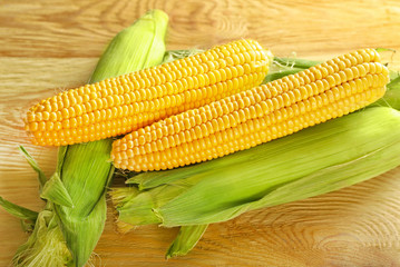 Fresh corn cobs on wooden table