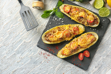 Slate plate with meat stuffed zucchini boats on wooden table