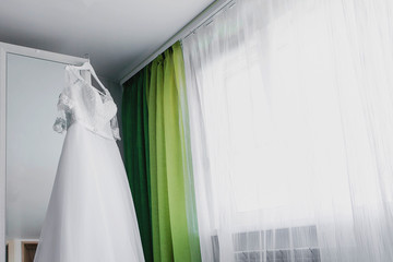 Beautiful wedding dress. Bride in beautiful dress standing at the window in studio interior
