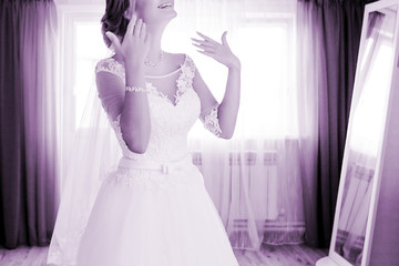 Beautiful wedding dress. Bride in beautiful dress standing at the window in studio interior