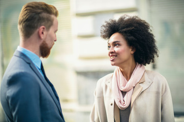 Two business people in an informal conversation in front of a business building