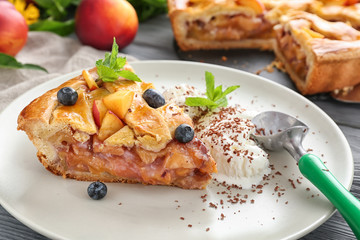Piece of tasty homemade peach pie and ice-cream on plate, closeup