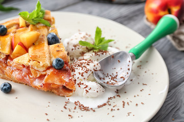 Piece of tasty homemade peach pie and ice-cream on plate, closeup