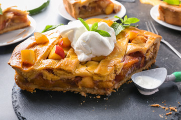 Tasty homemade peach pie with ice-cream on table, closeup