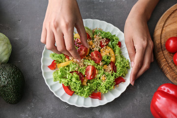 Woman preparing healthy salad on grey table, closeup