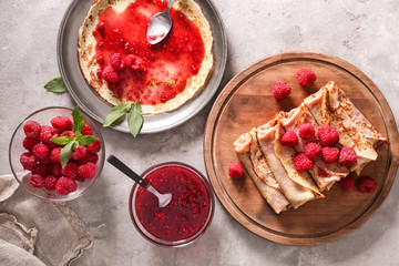 Composition with tasty thin pancakes, berries and jam on light table