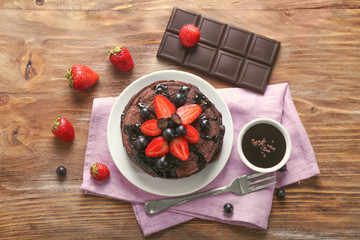 Plate with tasty chocolate pancakes and berries on wooden table
