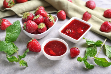 Bowls with delicious strawberry jam on light table