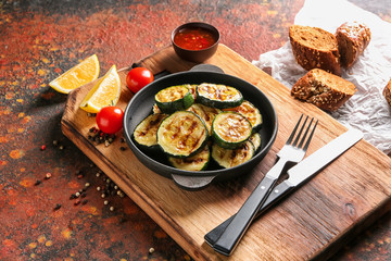 Pan with tasty grilled zucchini on wooden board