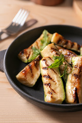 Pan with tasty grilled zucchini on wooden table
