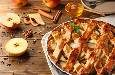 Dish with delicious apple pie on wooden table