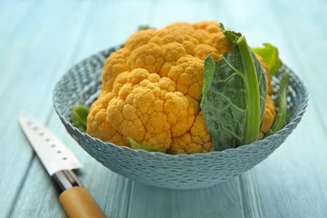 Wicker basket with yellow cauliflower on wooden table