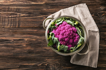 Colander with purple cauliflower on wooden table