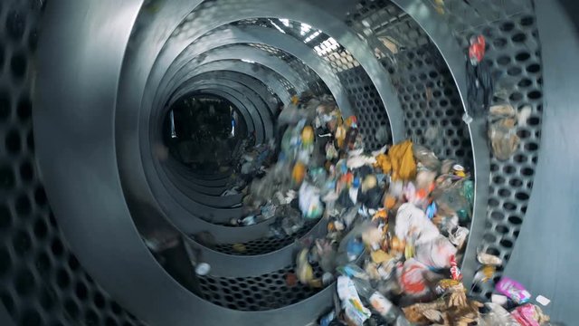 Trash is revolving inside an industrial recycling machine. Waste recycling equipment.